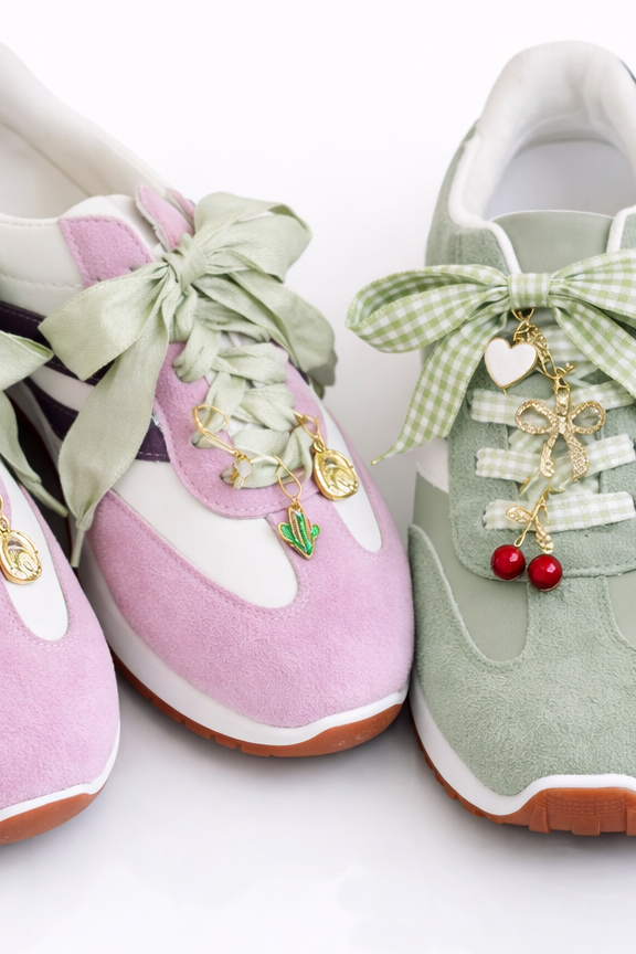 Pair of pink and green sneakers with decorative bows and charms on a white background