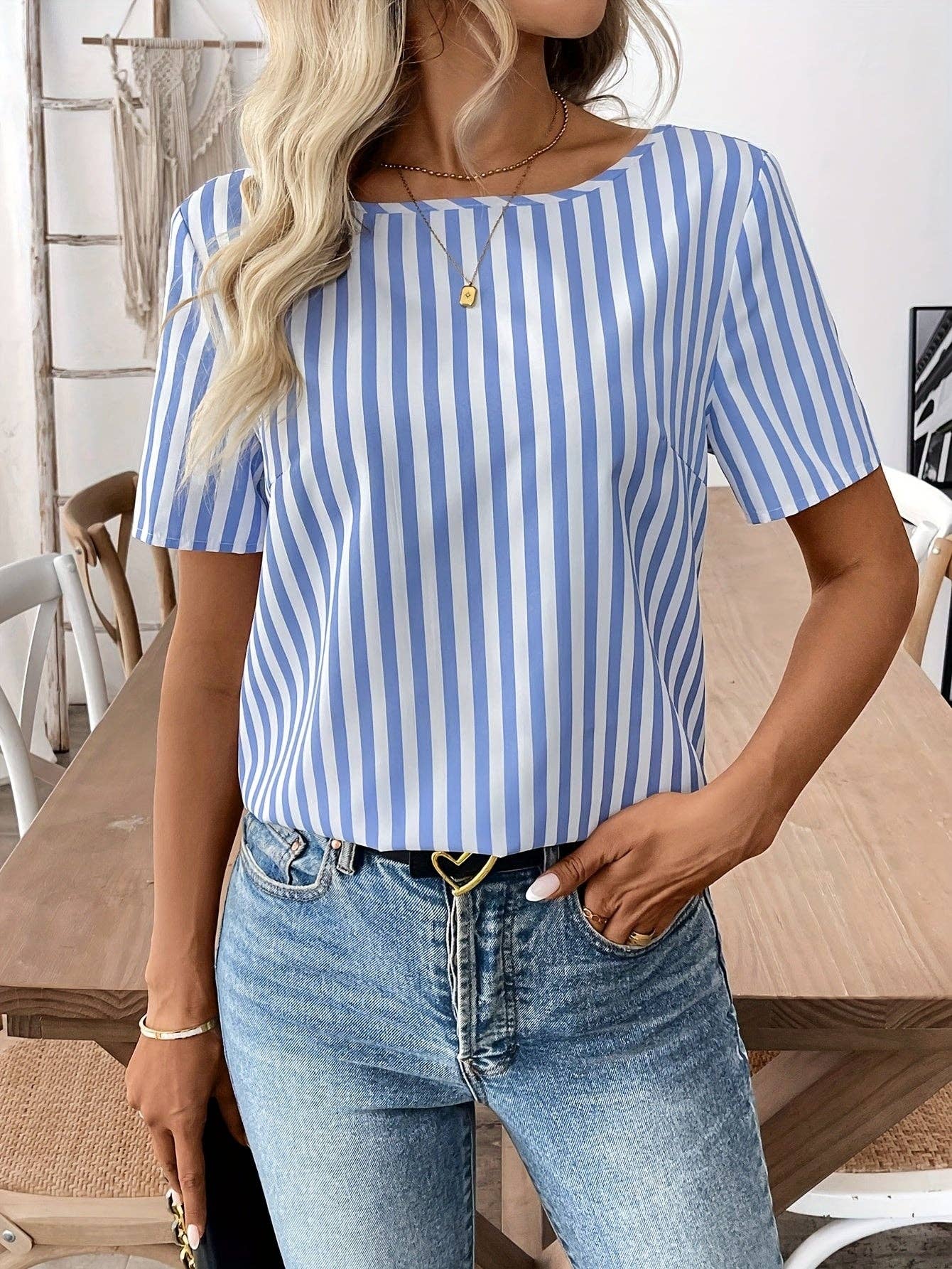 Person wearing a blue and white striped shirt and jeans indoors.