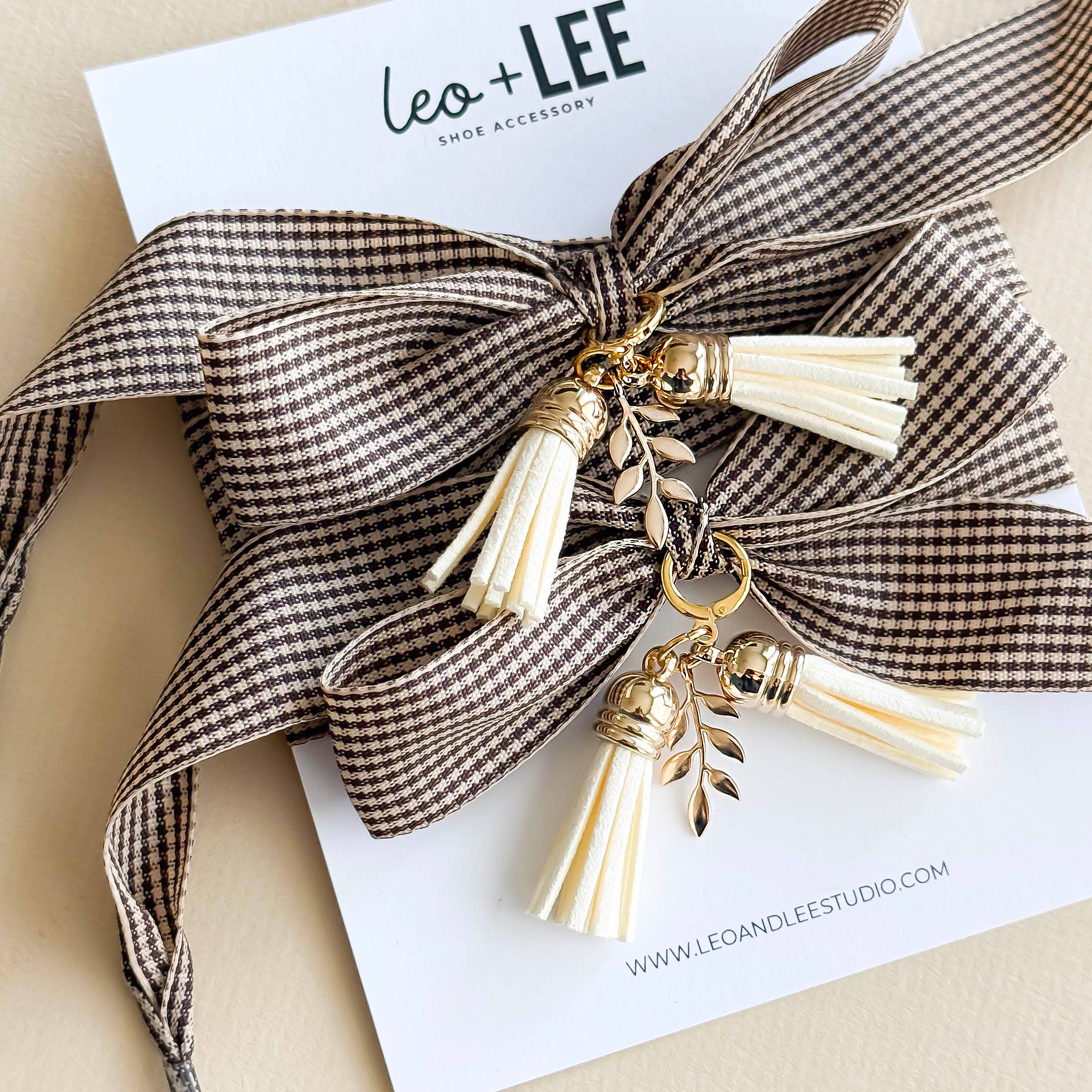 Bow tie shoe accessory with tassels on a white card with 'Leo + Lee' branding.