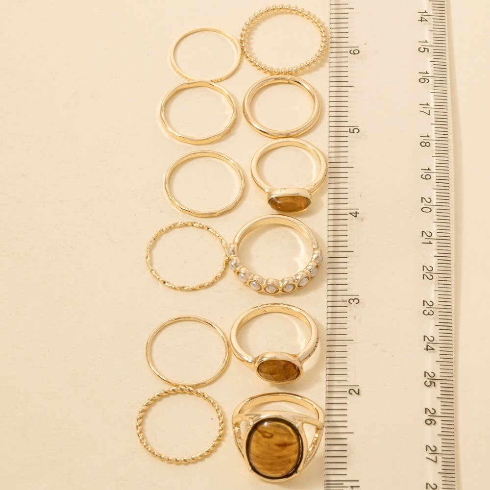 Gold rings with embedded stones on a beige surface with a ruler for scale.