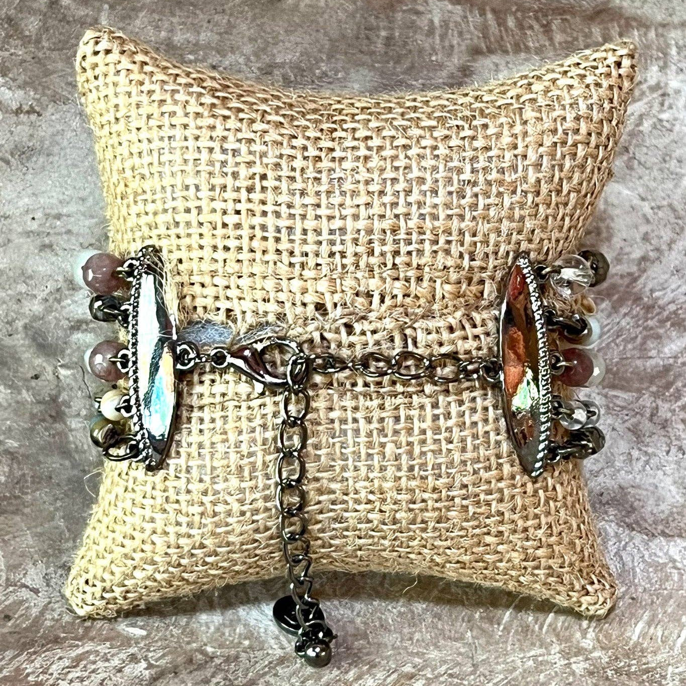 Bracelet with beads and chain on a burlap pillow