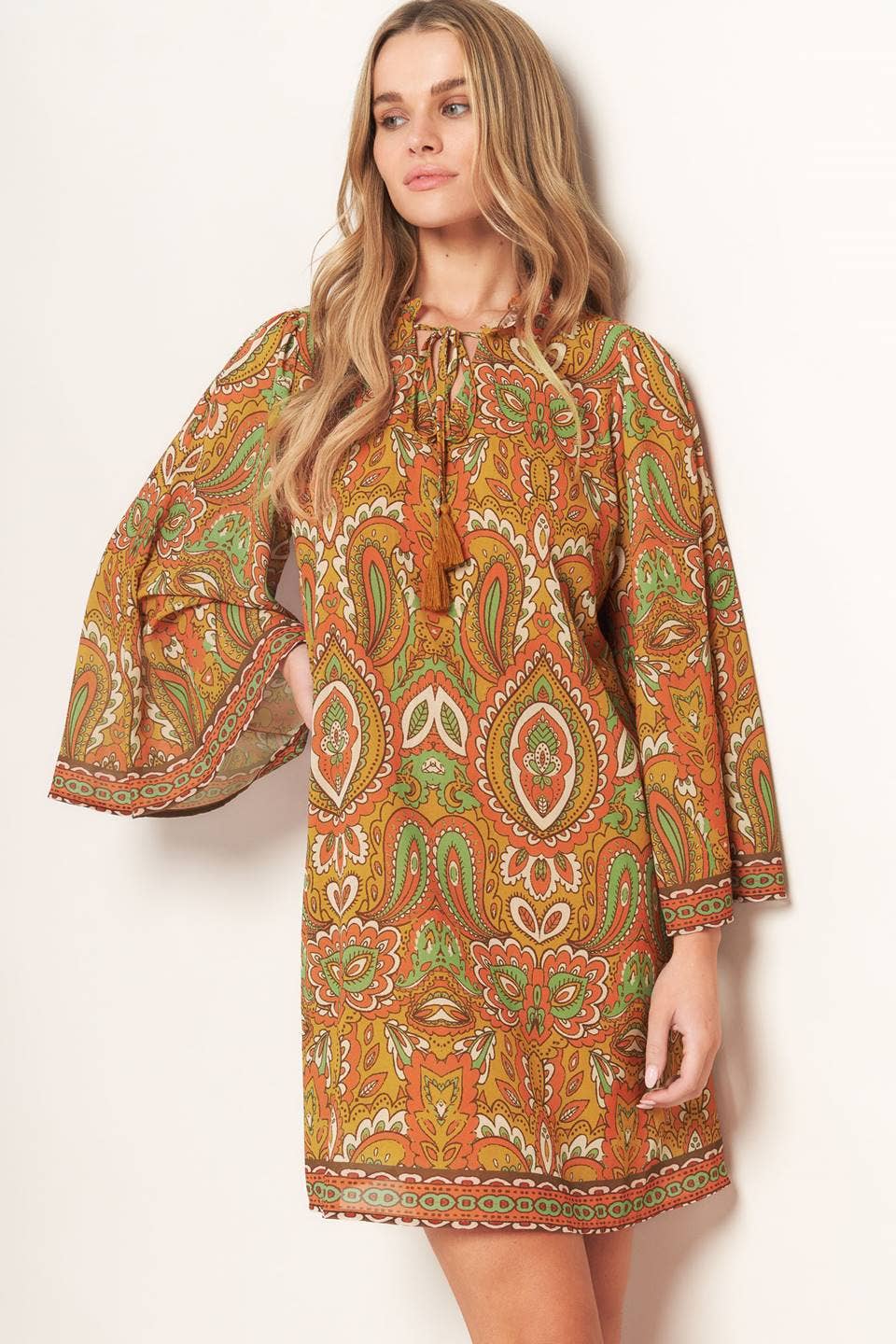 Woman wearing a patterned dress with long sleeves on a white background