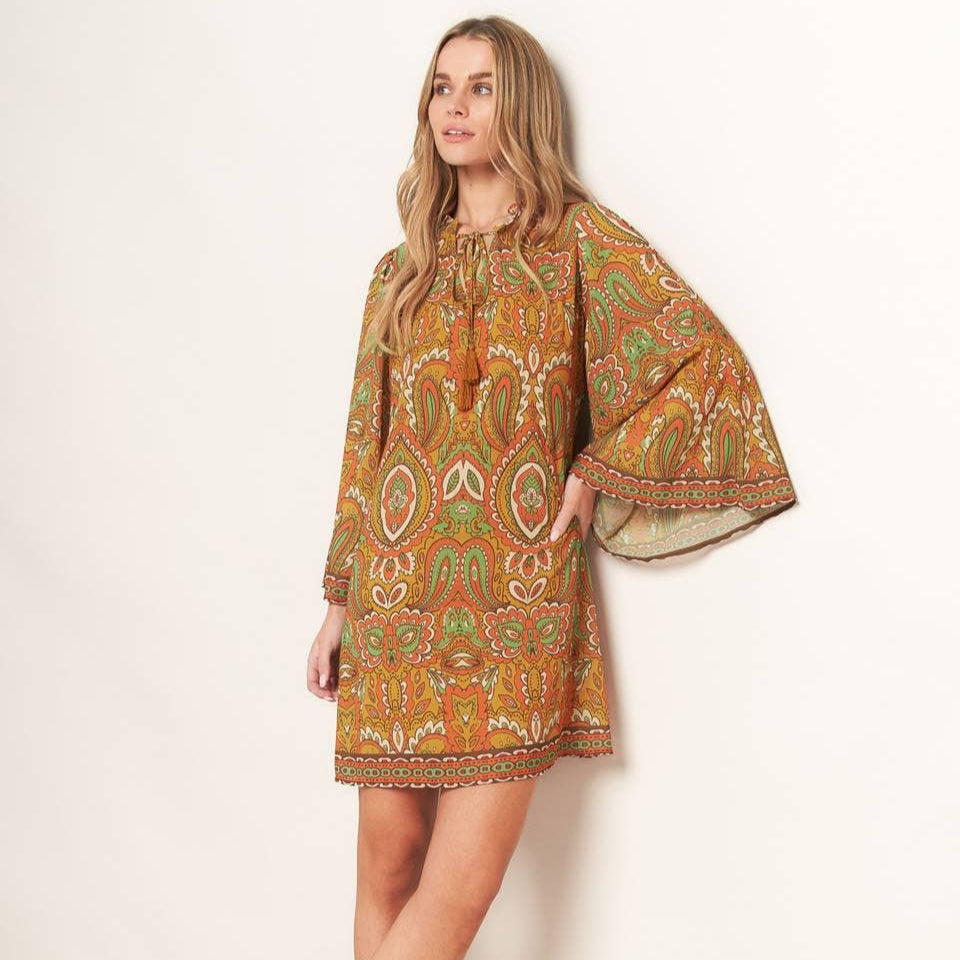 Woman wearing a patterned dress with bell sleeves on a white background
