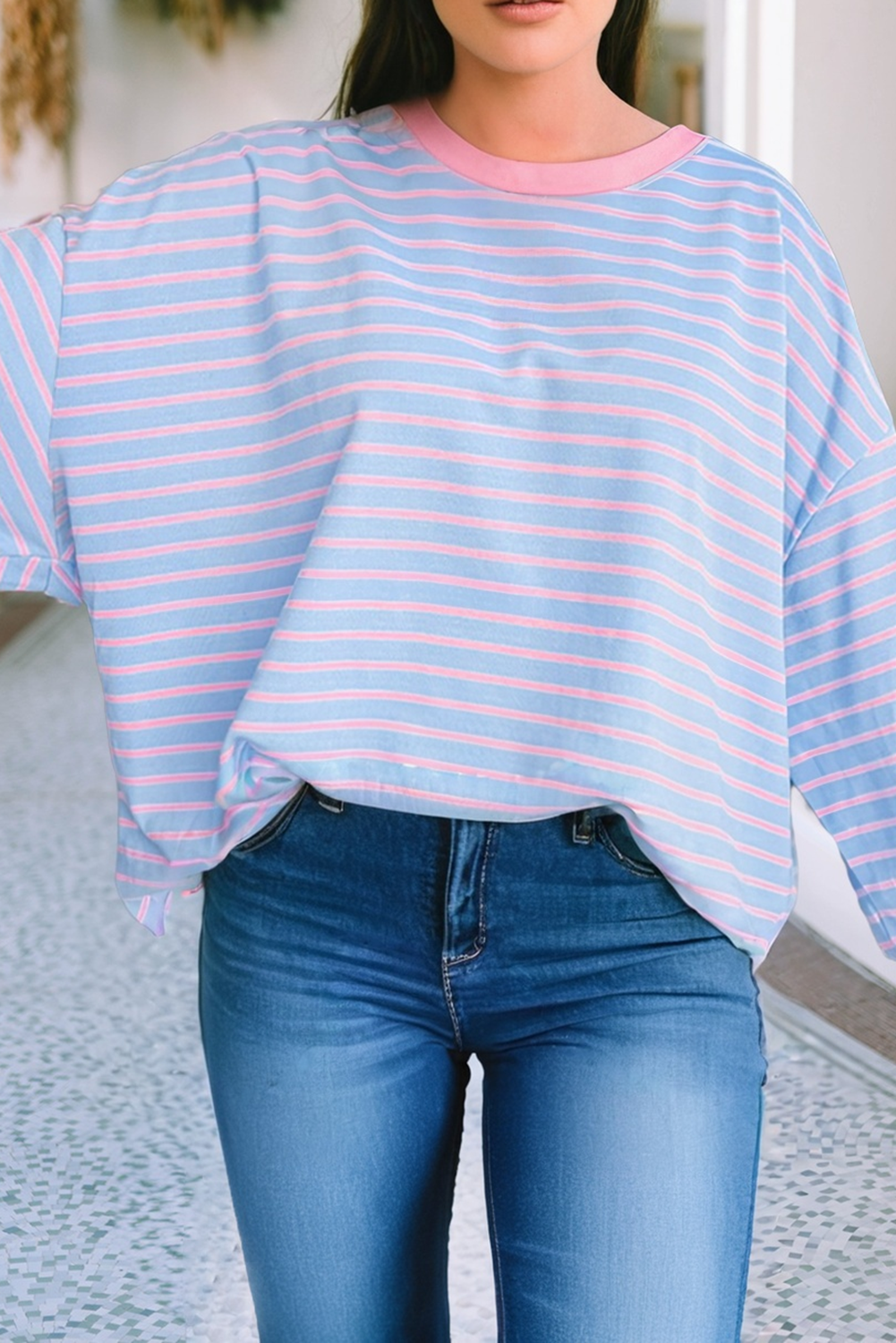 Person wearing a blue and pink striped shirt with a blurred background