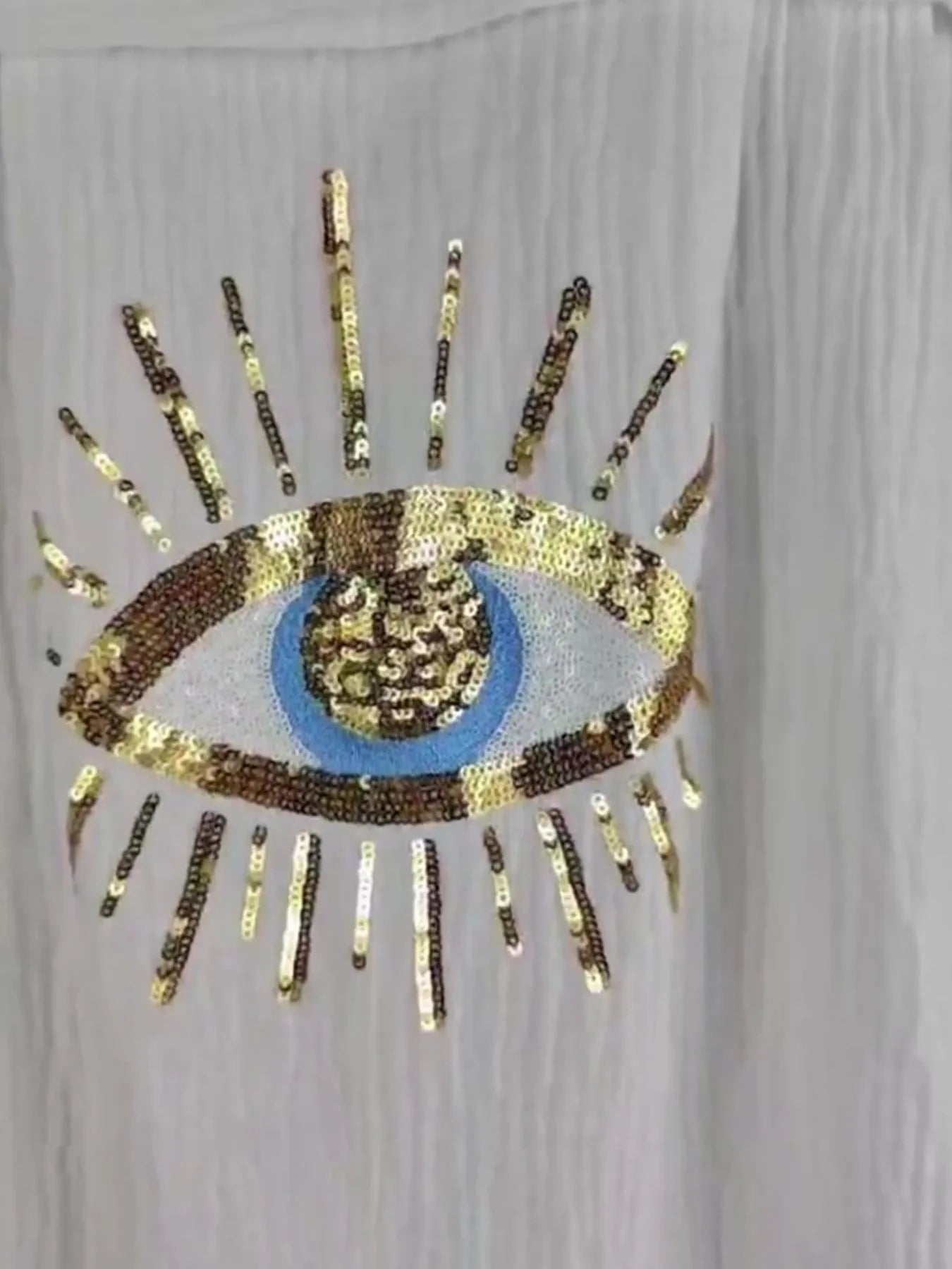 Sequined eye design on a plain background