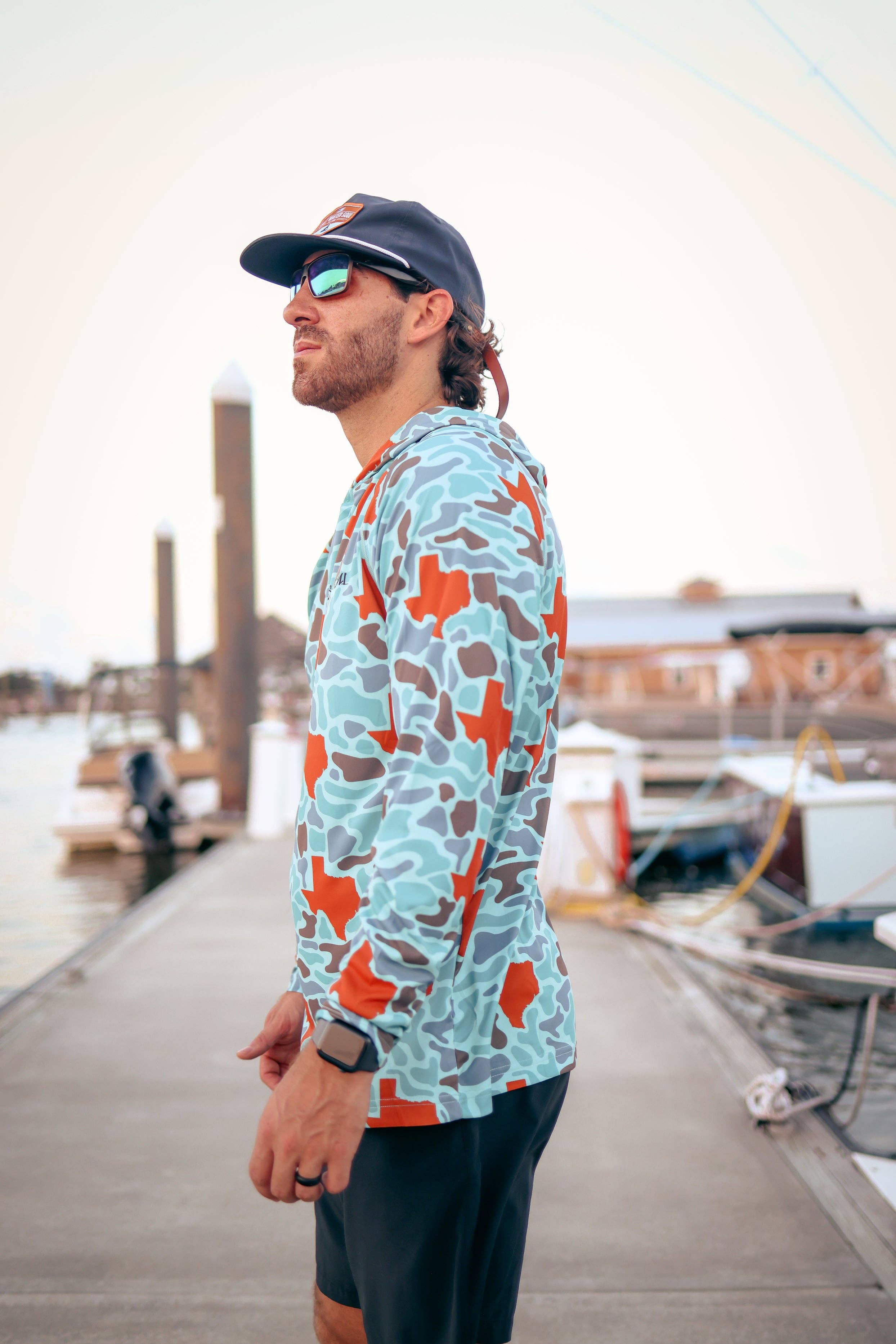 Man wearing a colorful patterned shirt and cap on a dock
