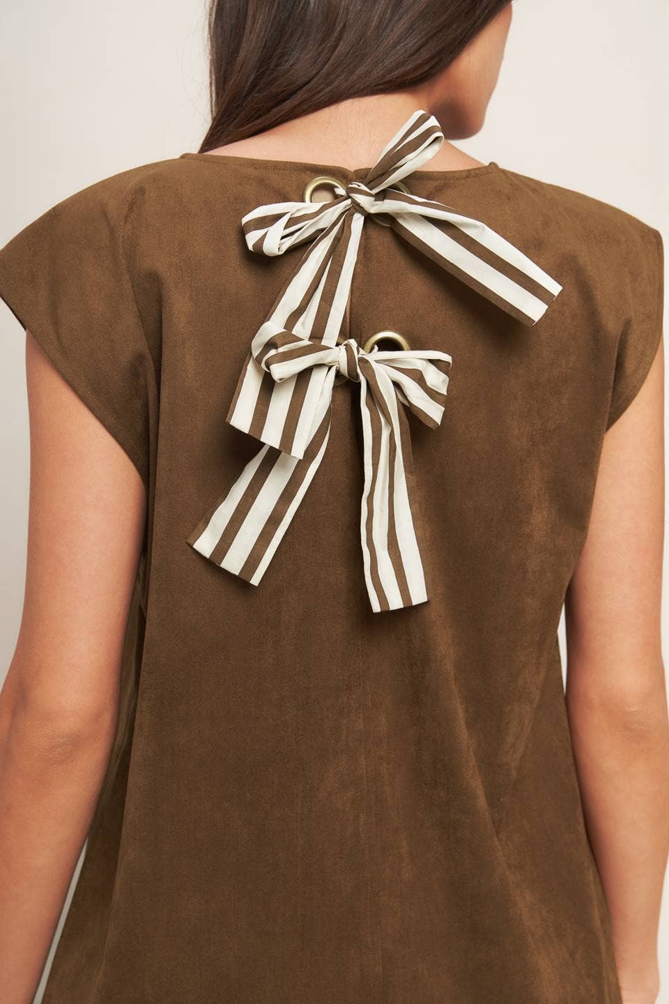 Brown top with striped bow details on the back against a neutral background