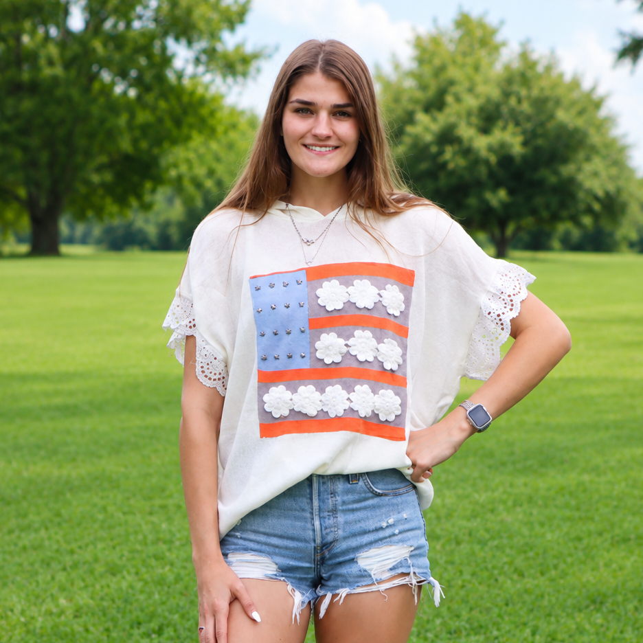 Woman wearing a white top with an American flag design in a grassy field