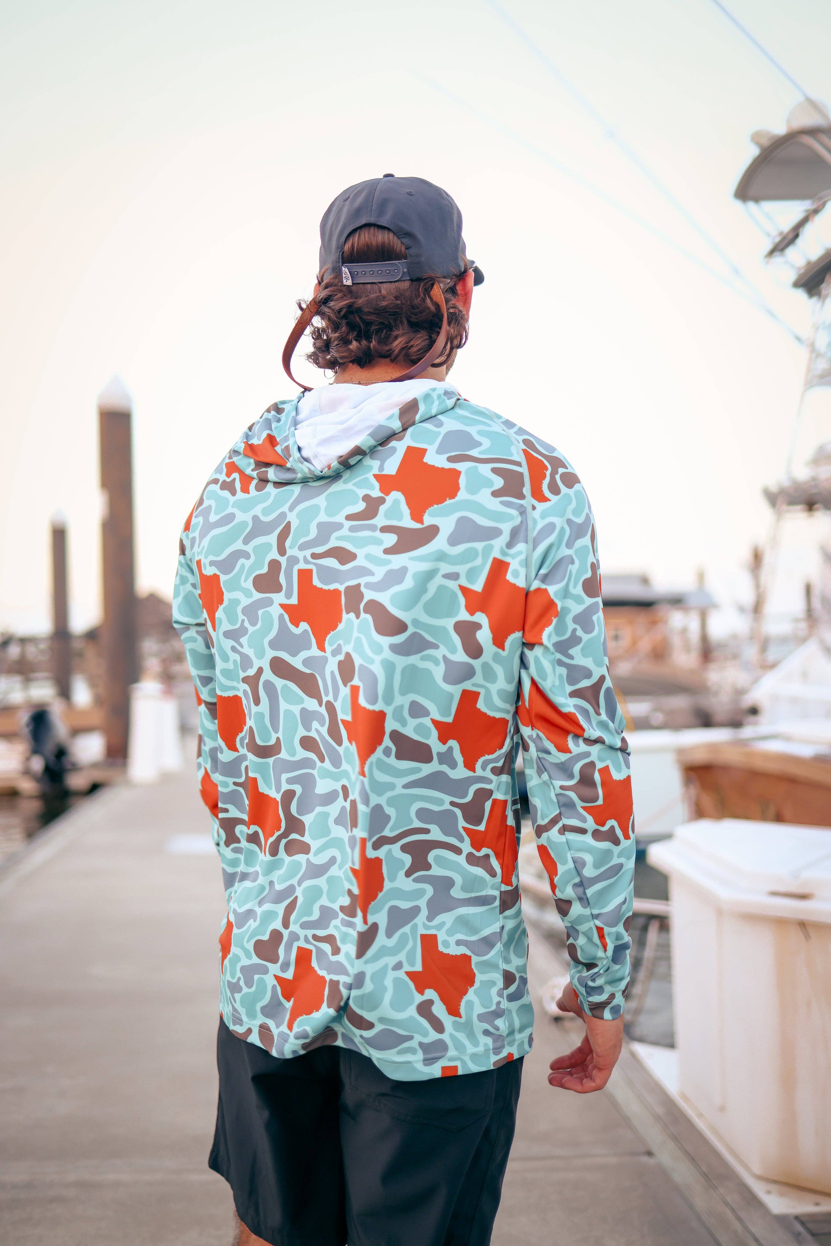 Person wearing a colorful Texas-shaped shirt on a dock