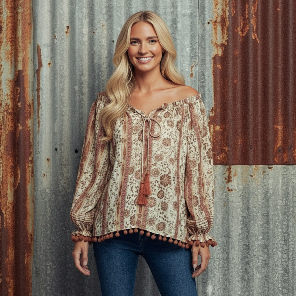 Woman wearing a patterned blouse and beige pants against a plain background