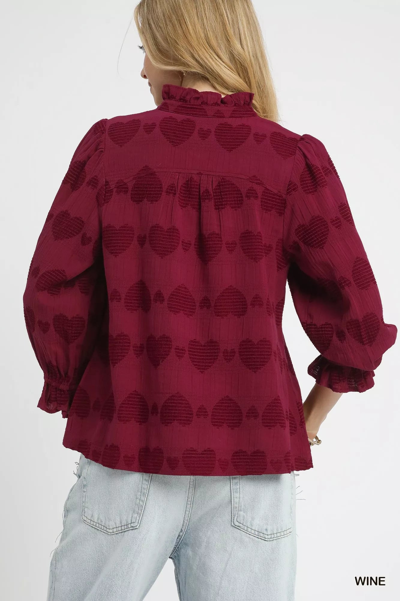 Red blouse with heart pattern worn by a person on a white background