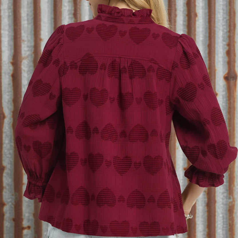 Red blouse with heart pattern worn by a person on a white background