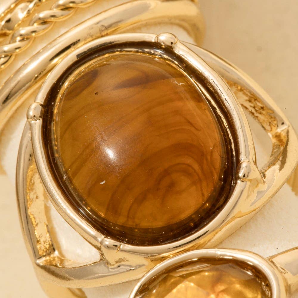 Gold ring with a large brown gemstone on a beige background