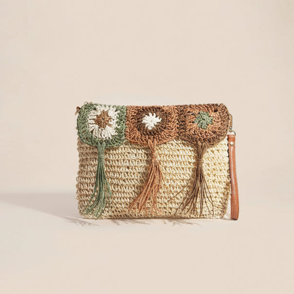 Woven clutch bag with floral patterns and tassels on a light background
