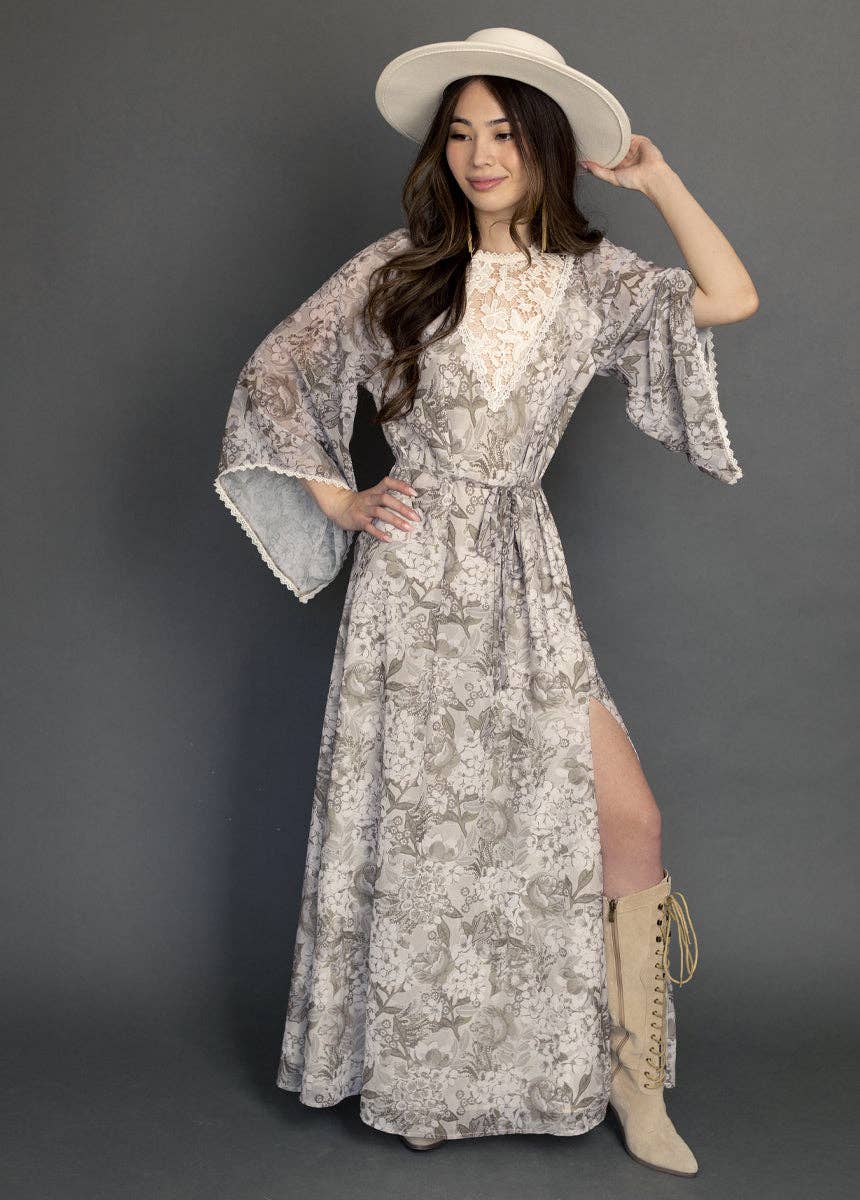 Woman wearing a floral dress with bell sleeves and a wide-brimmed hat against a gray background
