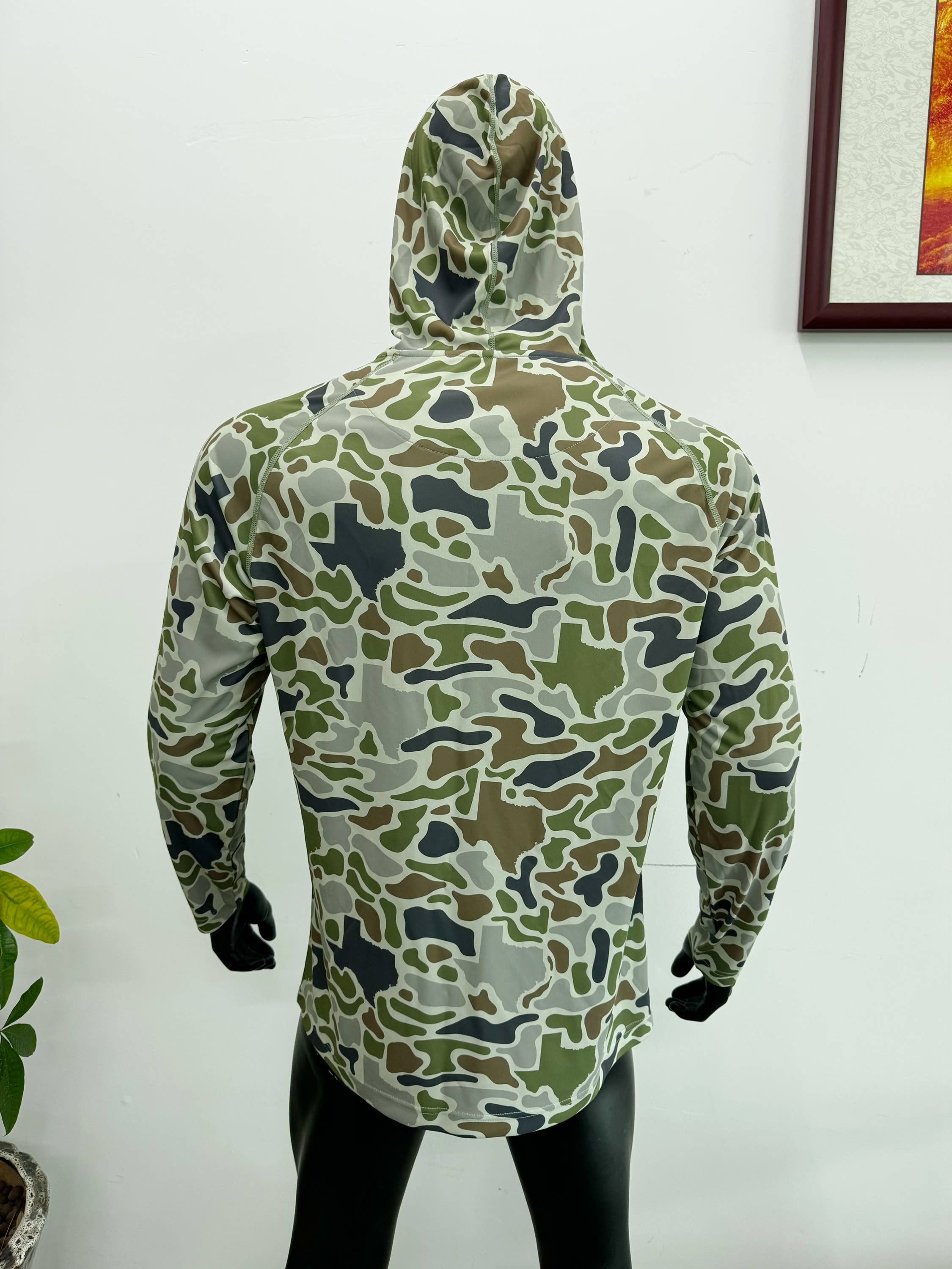 Camouflage-patterned raincoat on a mannequin against a white wall.