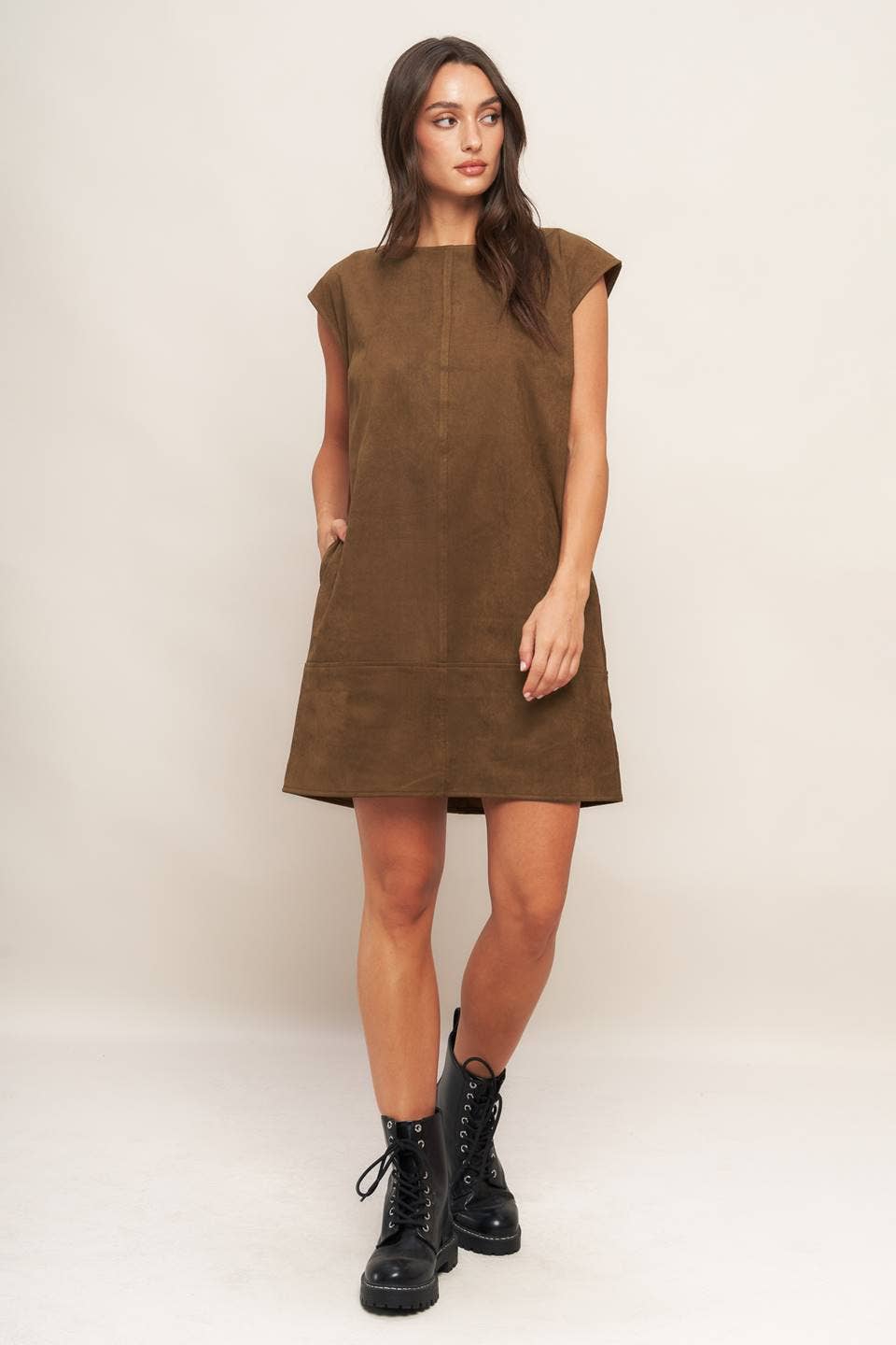 Woman wearing a brown dress with black boots on a white background