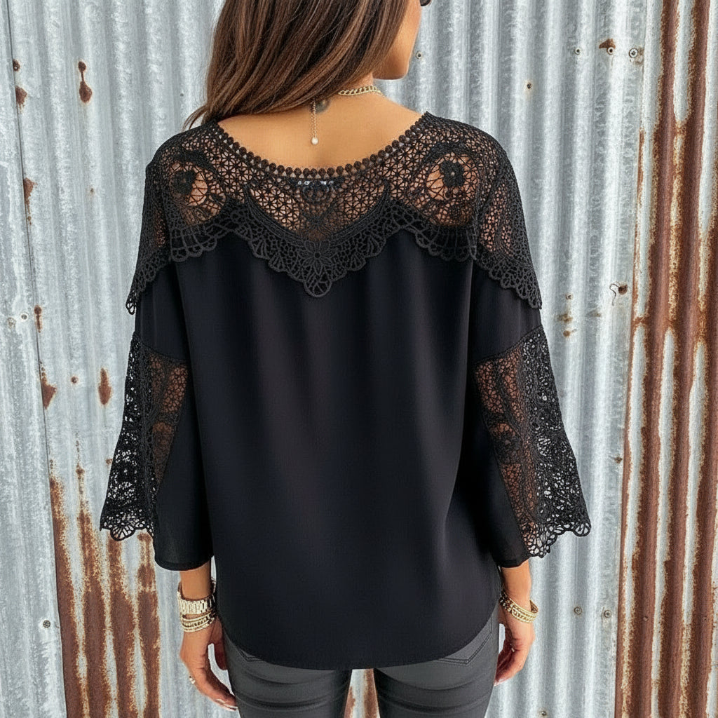 Black blouse with lace detailing worn by a person, with a blurred background.