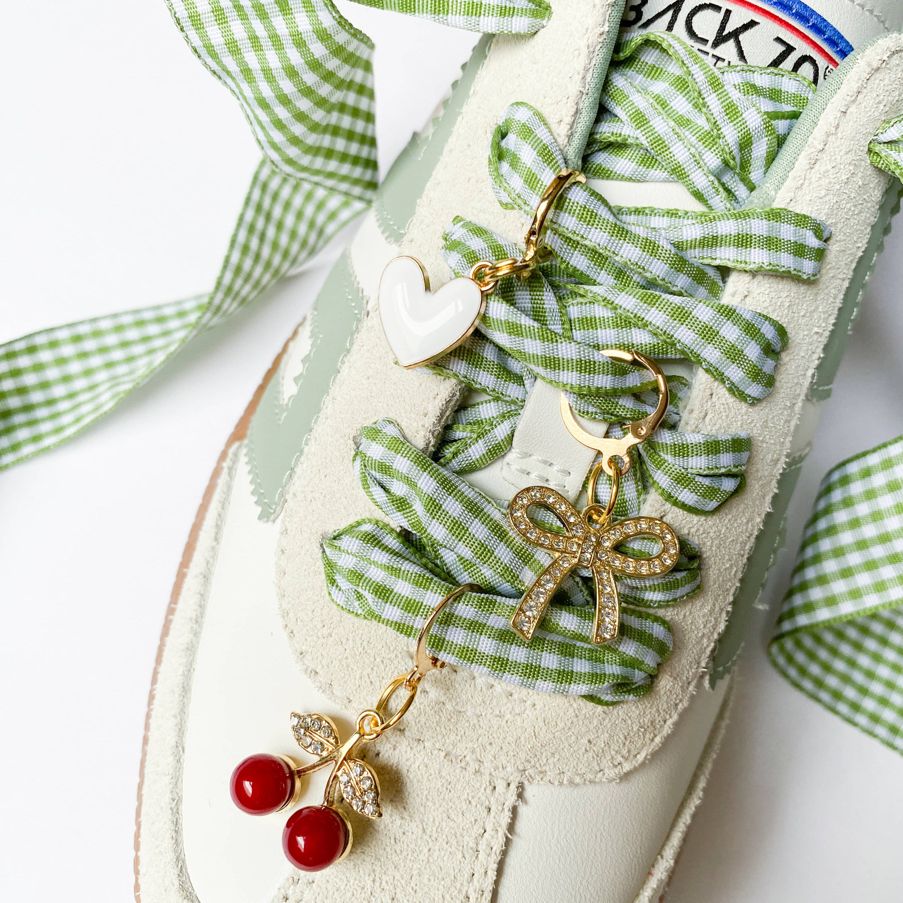 Decorative shoe with green checkered ribbon and embellishments on a white background