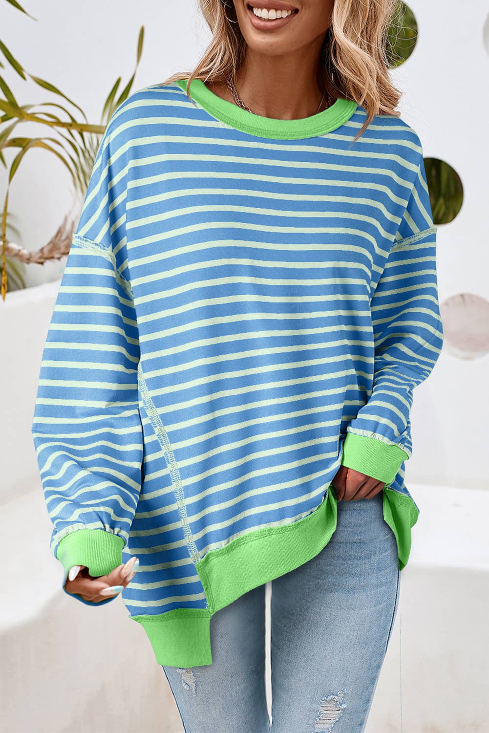 Woman wearing a blue and green striped sweater with a white background
