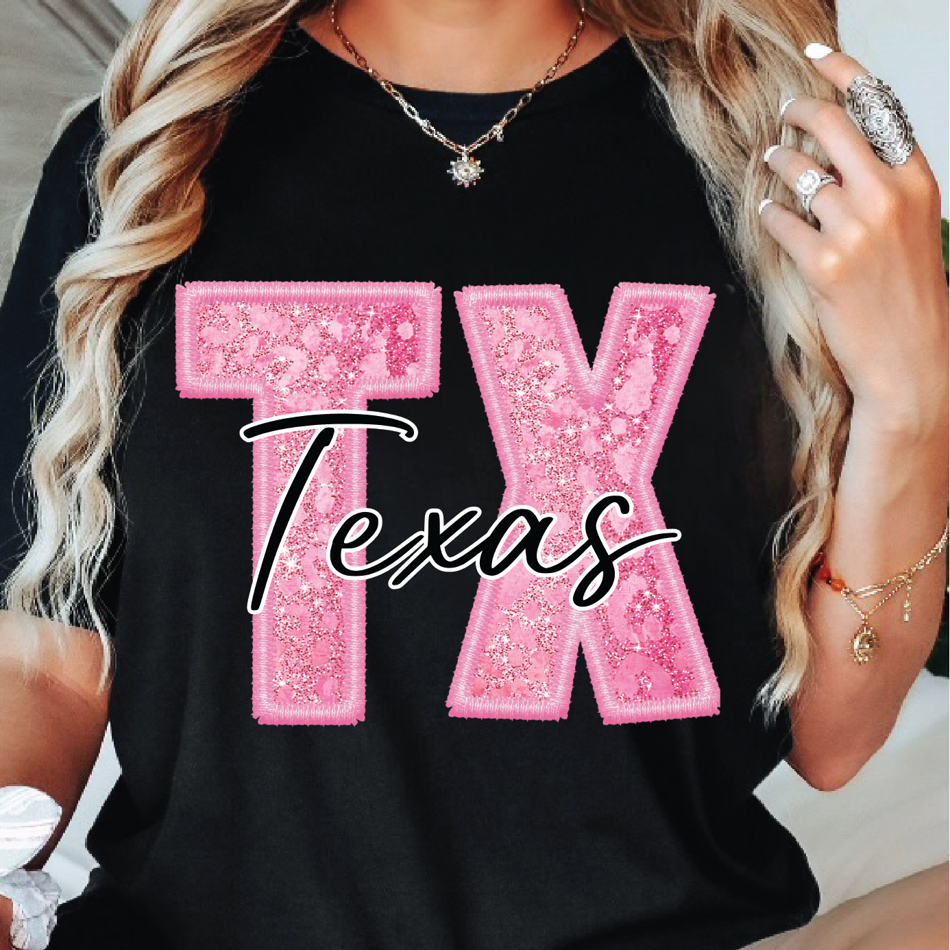 Person wearing a black t-shirt with pink 'TX Texas' design.