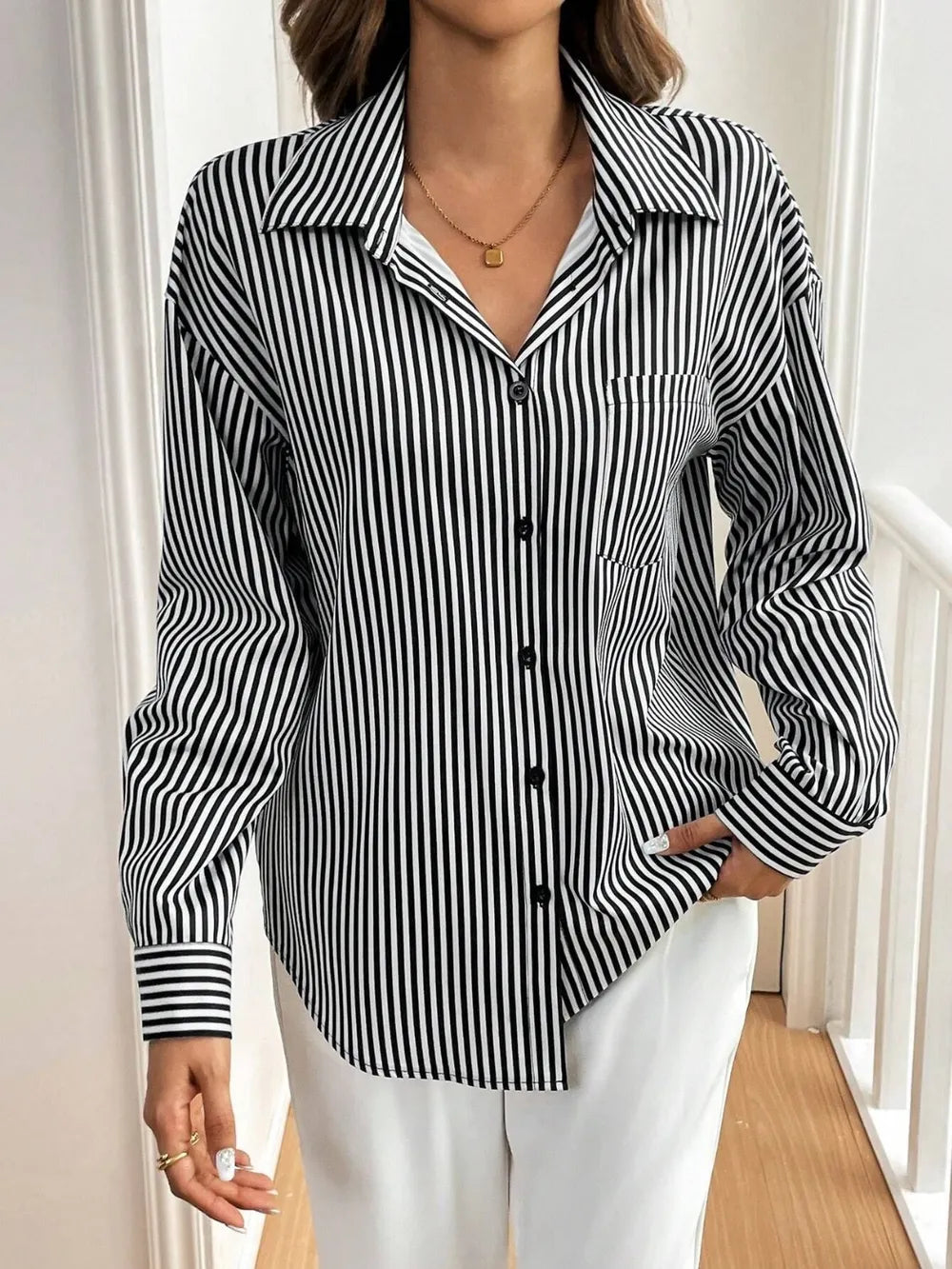 Person wearing a black and white striped shirt with a neutral background