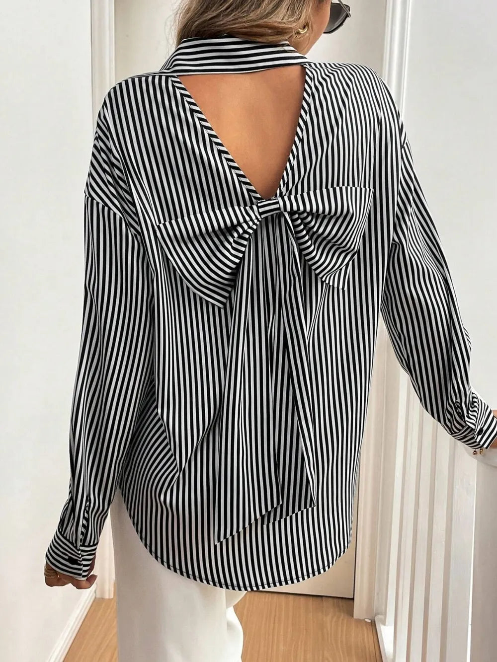 Black and white striped blouse with open back worn by a person indoors.