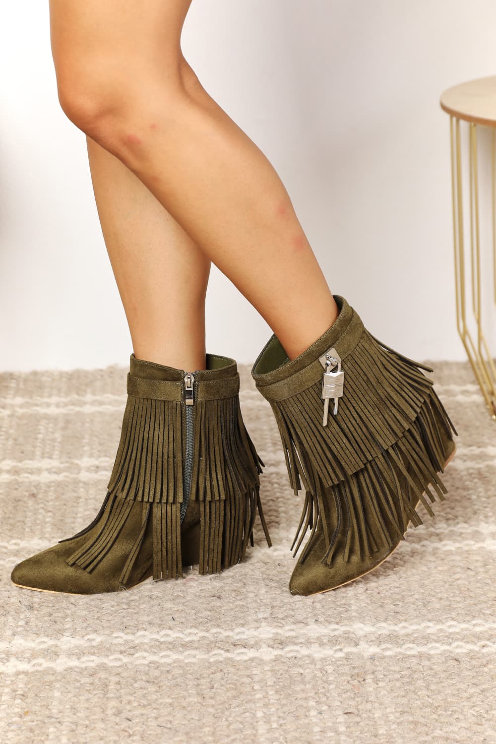 Green fringe boots worn by a person on a neutral background