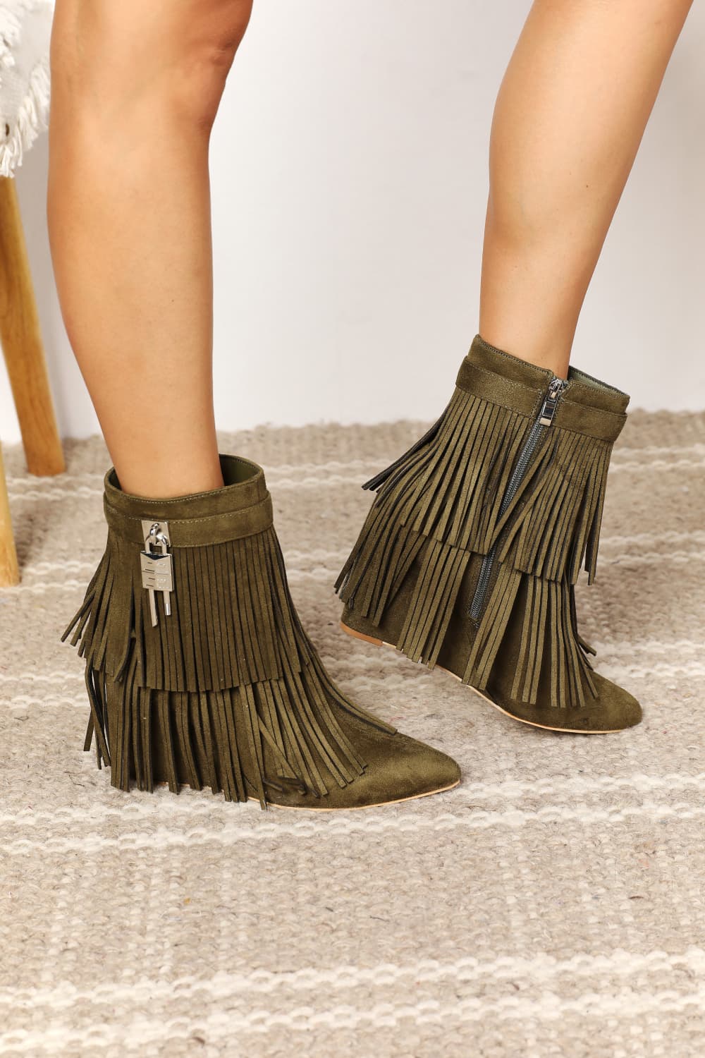 Green fringe boots worn by a person on a neutral background
