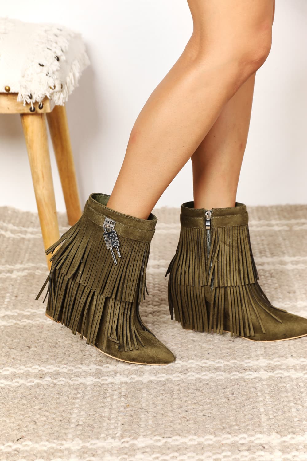 Green fringe boots worn by a person on a light background