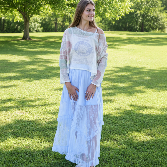 Woman in a light dress standing in a grassy field with trees in the background