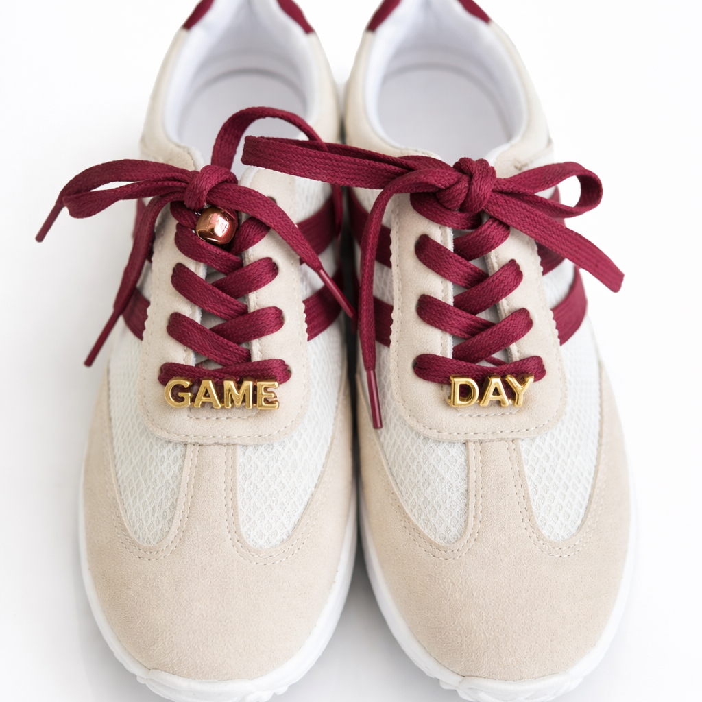 Pair of white sneakers with red laces and 'GAME DAY' text on a white background