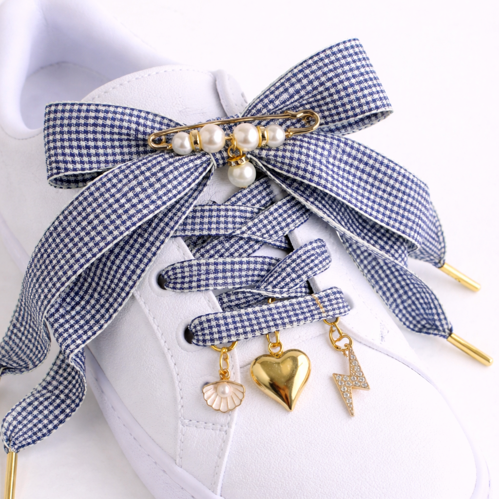 White sneaker with blue checkered shoelaces featuring gold charms on a white background