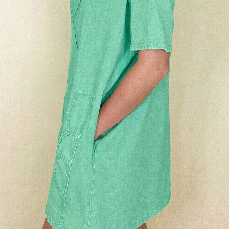 Woman wearing a green t-shirt dress against a beige background