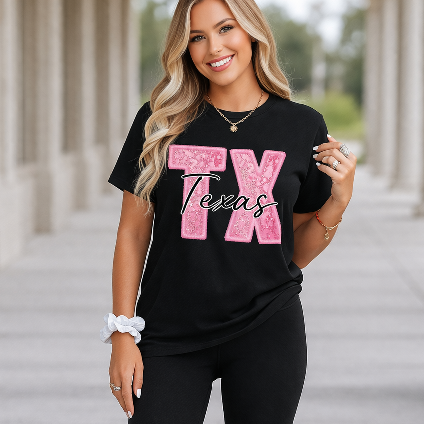 Woman wearing a black t-shirt with 'TX Texas' in pink and black leggings outdoors.