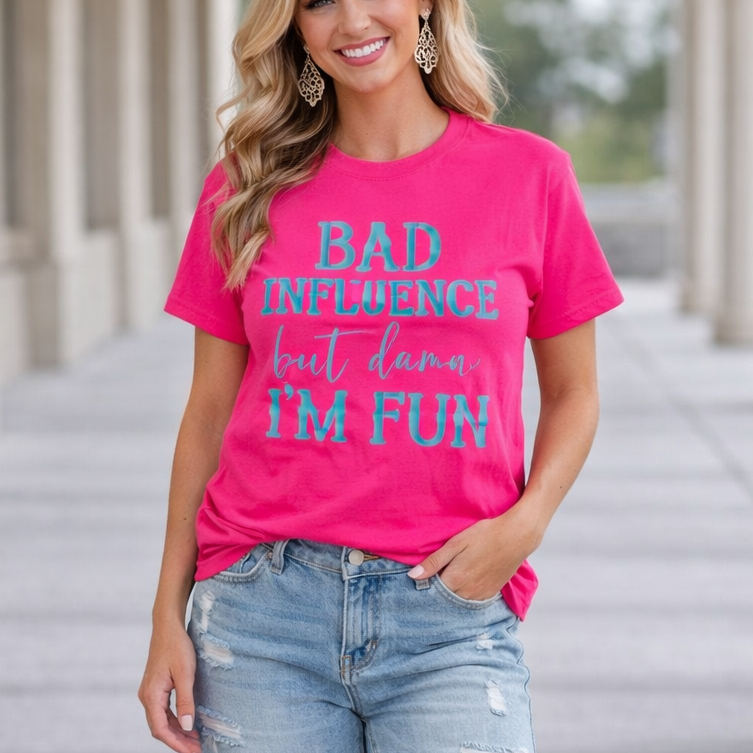Woman wearing a pink t-shirt with text and denim shorts standing on a pathway.