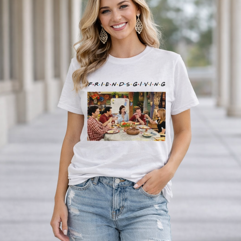 Woman wearing a 'Friendsgiving' t-shirt with a graphic of people around a table, standing on a covered walkway.