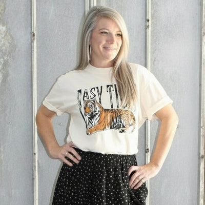 Person standing on a set of stairs wearing a white t-shirt and black patterned skirt.