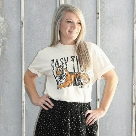 Person standing on a set of stairs wearing a white t-shirt and black patterned skirt.
