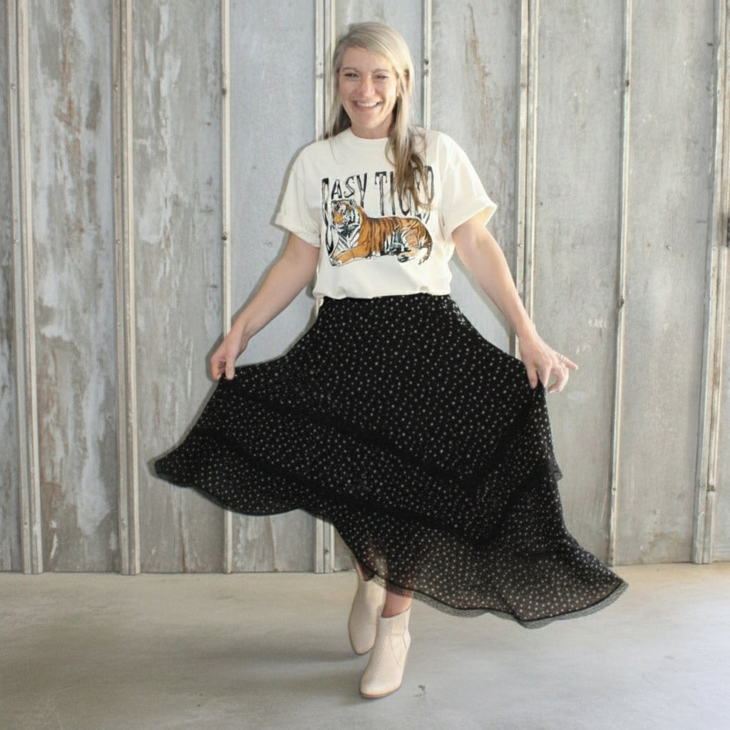 Person holding a black polka dot skirt against a wooden wall.