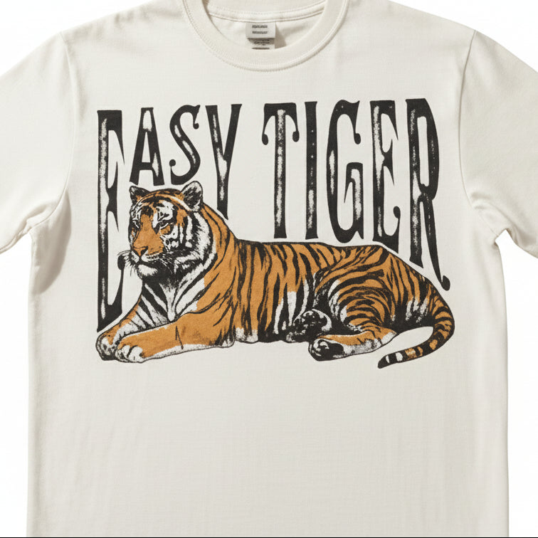 White t-shirt with a tiger graphic and 'Easy Tiger' text on a textured surface.