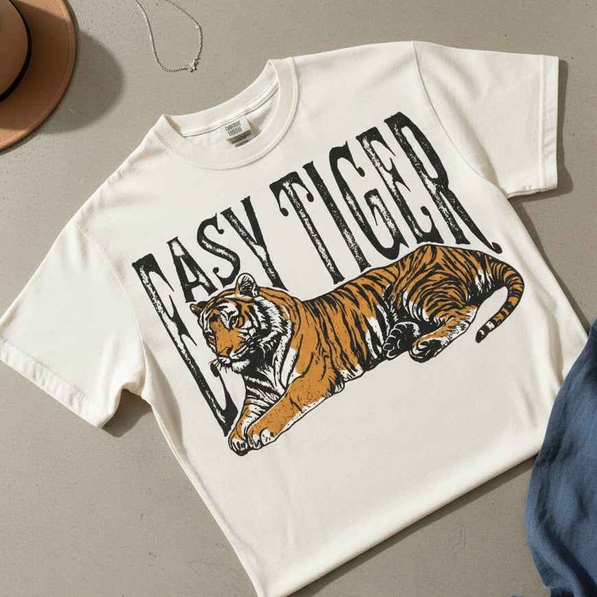 White t-shirt with a tiger graphic and 'Easy Tiger' text on a textured surface.