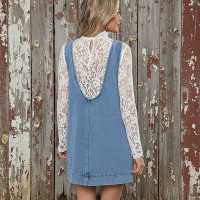 Woman wearing a denim dress with a white bra underneath, standing outdoors.