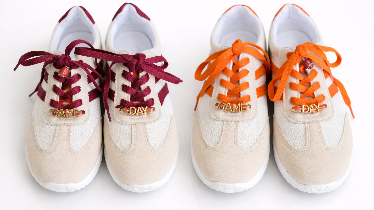 Two pairs of white sneakers with red and orange laces on a white background