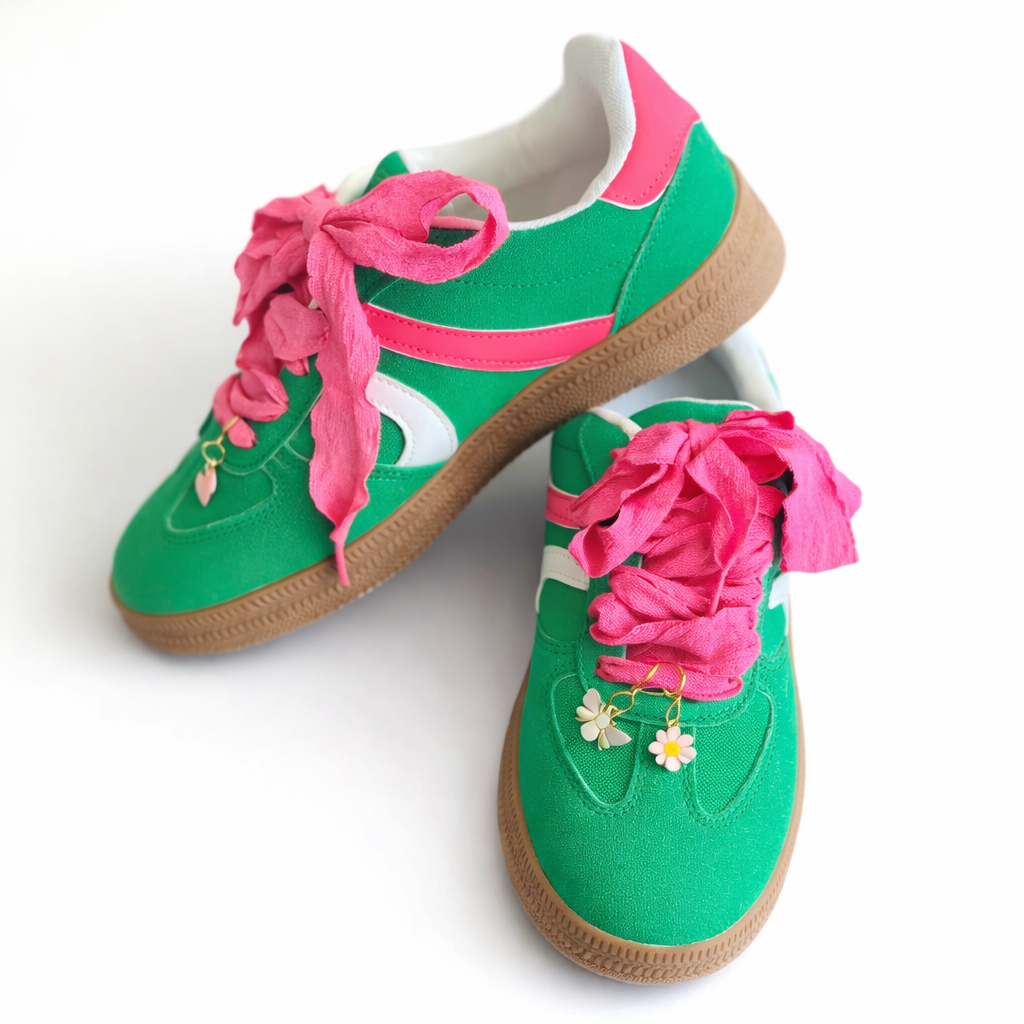 Green sneakers with pink laces on a white background