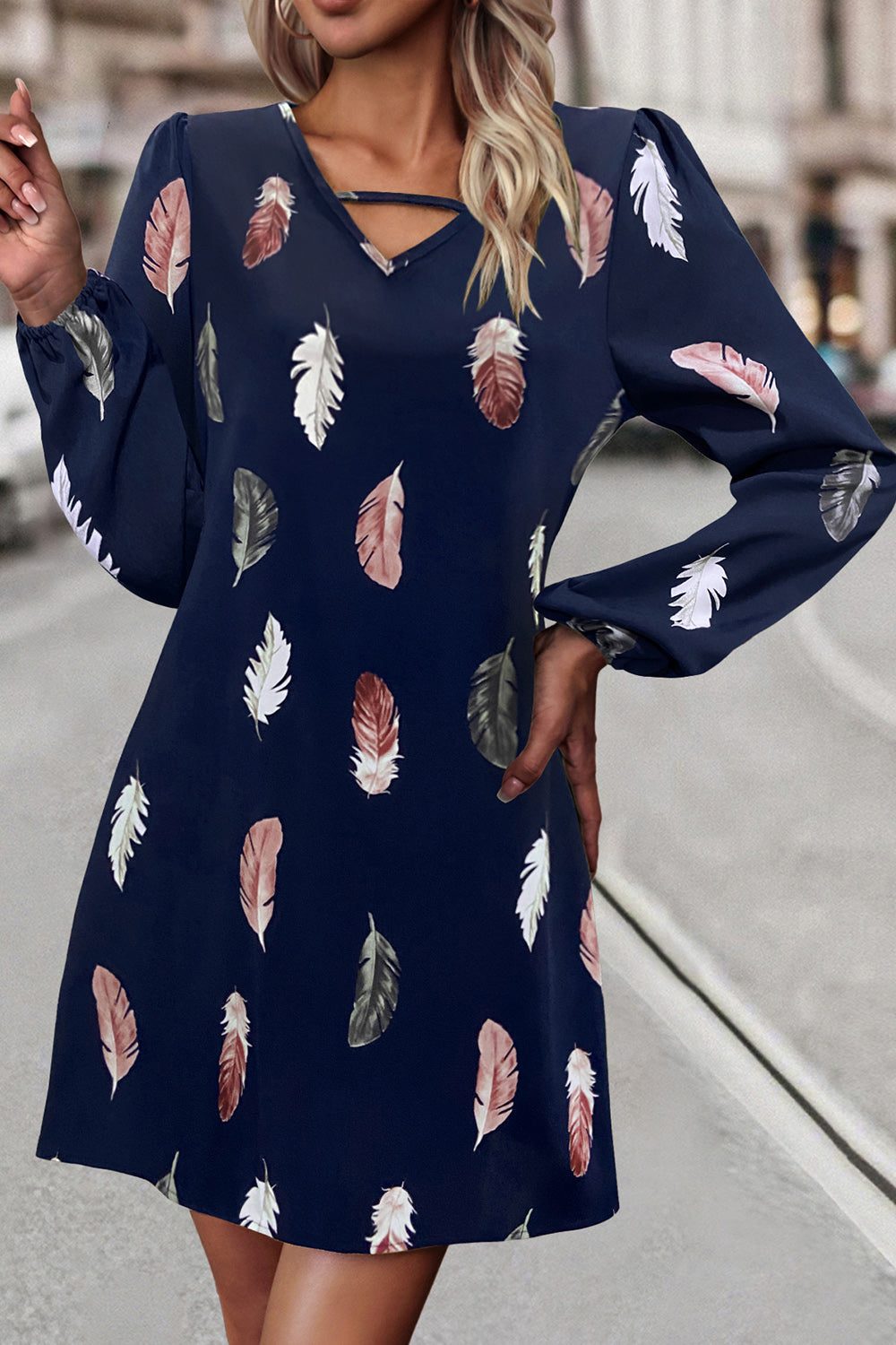Navy blue dress with feather pattern worn by a person on a blurred street background