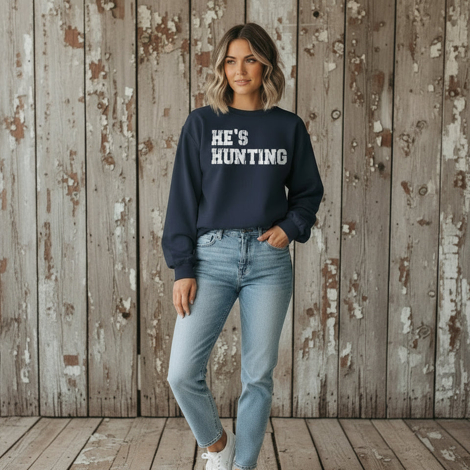 Person wearing a navy sweatshirt with 'HE'S HUNTING' text.