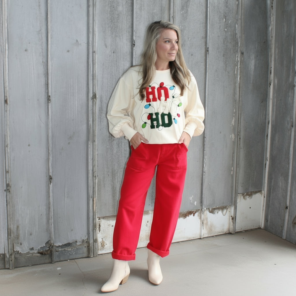 Person wearing a white sweatshirt with red text and red pants standing on a wooden staircase.