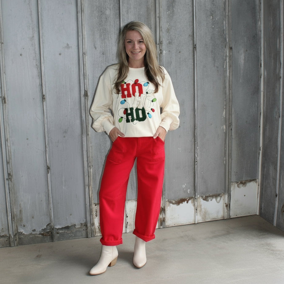 Person wearing a white sweatshirt with colorful text and red pants standing on steps.