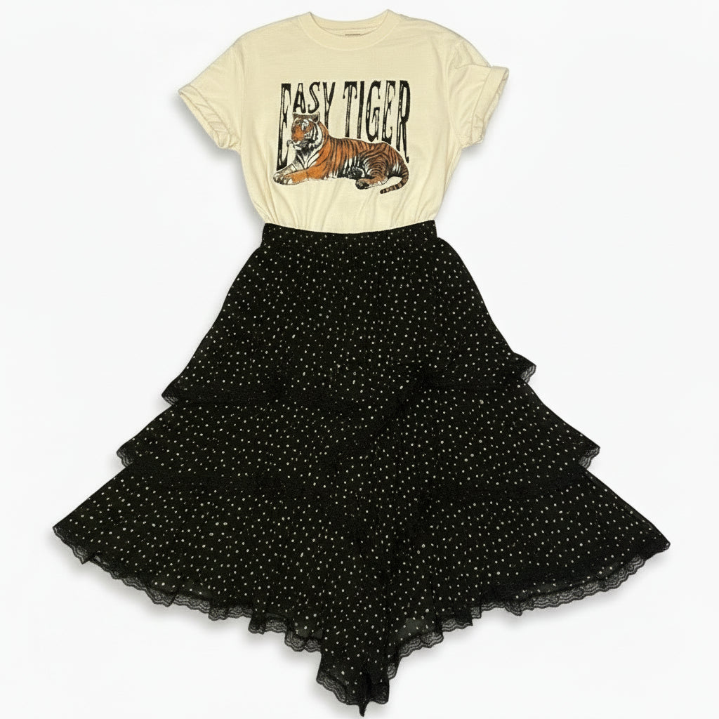 Black textured fabric and beige t-shirt with tiger design on a wooden floor.